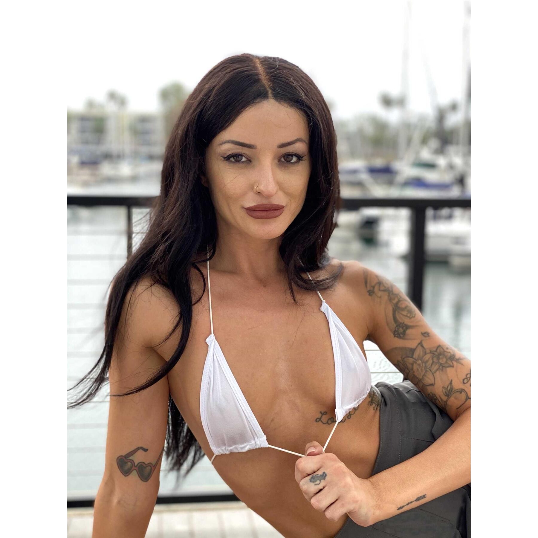Brunette female posed outdoors wearing bikini displaying cleavage